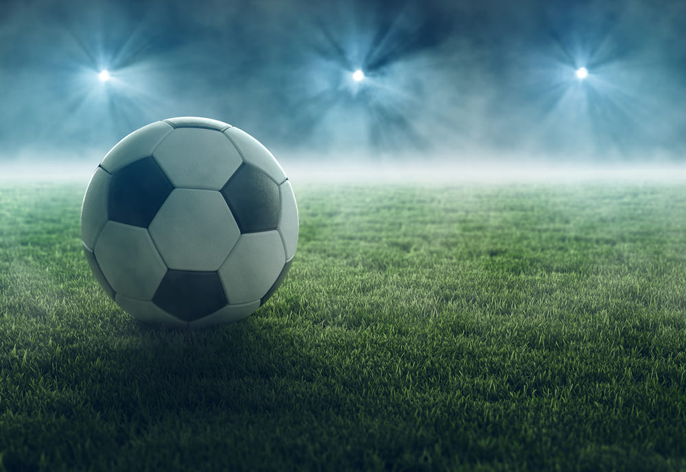 Fußball auf mit Flutlichtanlage beleuchtedem Rasen