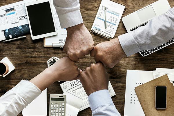 4 Fäuste schlagen ab über Schreibtisch